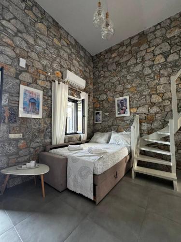 a bedroom with a bed and a stone wall at Casa Petra Astypalea in Astypalaia