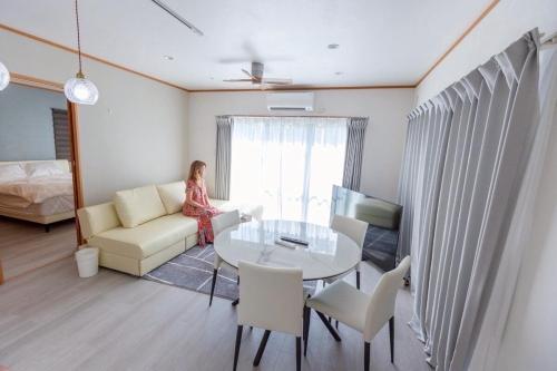 a woman sitting on a couch in a living room at 星空テラスと海一望 静寂に包まれる屋上BBQ Resort Villa ManMaka in Miyakojima