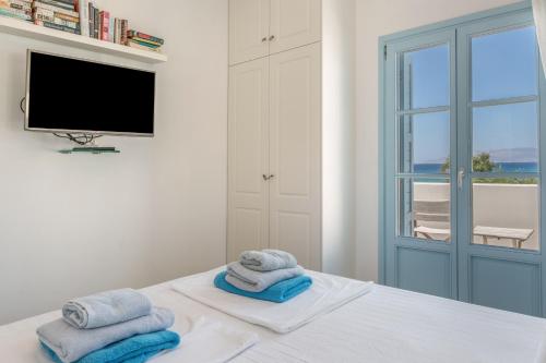 a room with towels on a bed with a television at Beachfront Ios Villa in Ios Chora