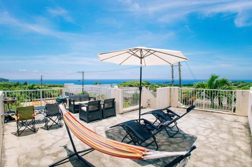 a patio with a hammock and an umbrella at 星空テラスと海一望 静寂に包まれる屋上BBQ Resort Villa ManMaka in Miyakojima