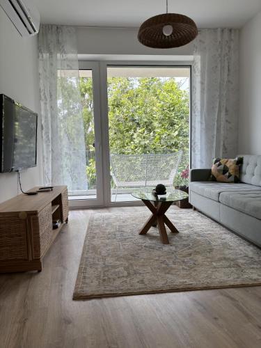 a living room with a couch and a large window at Olive II Apartman in Alsóörs