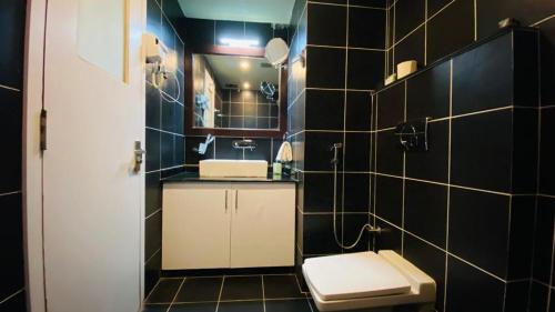 a black tiled bathroom with a toilet and a sink at Chitwan Grand Regency in Bharatpur