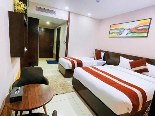a hotel room with two beds and a chair at Chitwan Grand Regency in Bharatpur