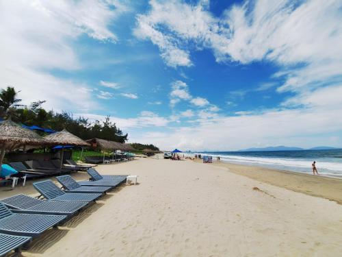 a beach with blue lounge chairs and the ocean at Heritage Gem Boutique Villa in Hoi An