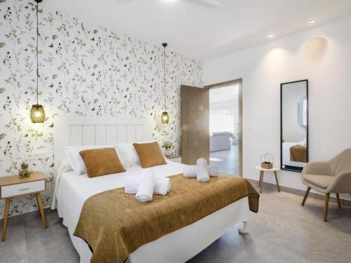 a bedroom with a large white bed and a chair at Casa Regalo in Dúrcal