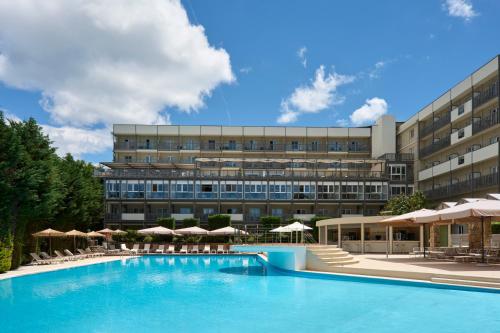 a hotel with a large swimming pool in front of a building at Ariti Grand Hotel in Corfu
