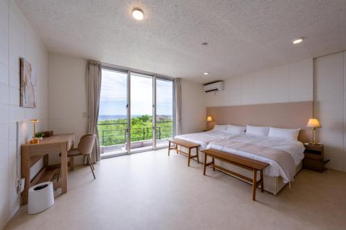 a bedroom with a bed and a desk and a large window at COCO VILLLA 沖縄今帰仁-Okinawa nakijin in Nakijin