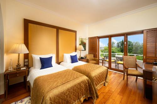 a hotel room with two beds and a balcony at The Oberoi Bengaluru in Bangalore