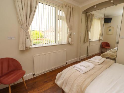 a bedroom with a bed and a mirror and a chair at Rose Briar Cottage in Morpeth
