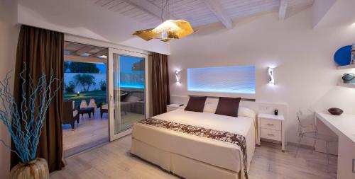 a white bedroom with a bed and a balcony at Destino di Nora in Pula
