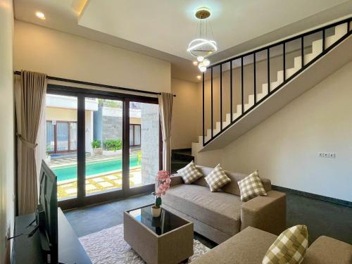 a living room with a couch and a sliding glass door at Mimpi Ayung Villas by AGATA in Bringkit