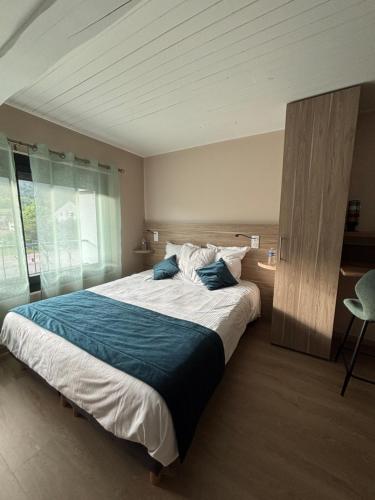 a bedroom with a large bed with a blue blanket at Oyonnax Bellignat Appart Hotel in Bellignat