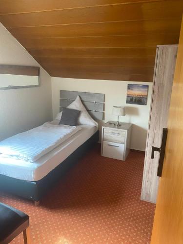 ein Schlafzimmer mit einem Bett und einem Tisch mit einer Lampe in der Unterkunft Hotel-Windeck in Burbach