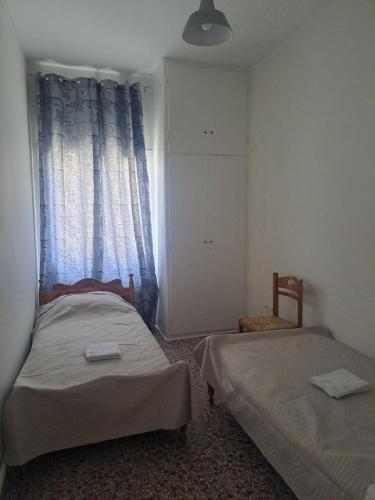 two beds in a small room with a window at Aspasia's apartment in Mytilene