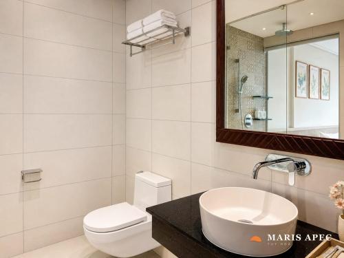 a bathroom with a sink and a toilet and a mirror at Maris Apec Tuy Hoà in Tuy Hoa