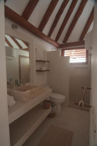 a bathroom with a sink and a toilet and a mirror at Tierra del Mar Hotel - Adults Only in Holbox Island