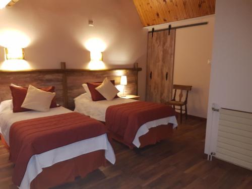 a hotel room with two beds and a chair at El Copihue Olmué in Olmué