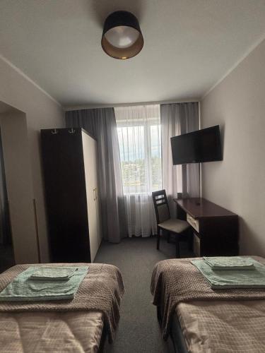 a hotel room with two beds and a desk and a window at 208 Apartment Ania in Koszalin