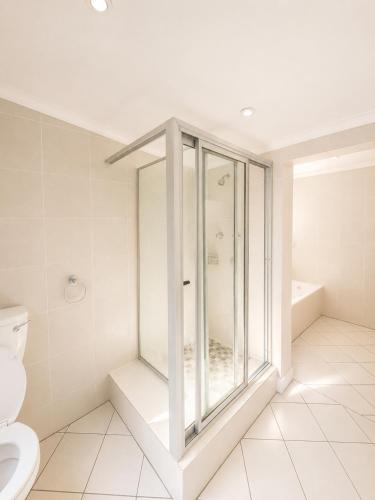 a bathroom with a glass shower and a toilet at 12 On Braemar Guesthouse in Cape Town