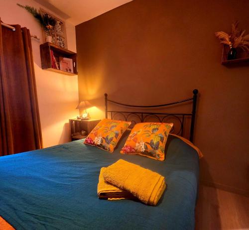 a bedroom with a bed with blue sheets and pillows at La Maison des Oiseaux in Crouzilles