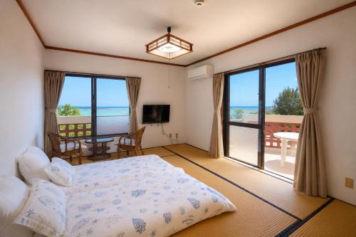 a bedroom with a bed and a view of the ocean at Beachside Pension Mibal in Nanjo