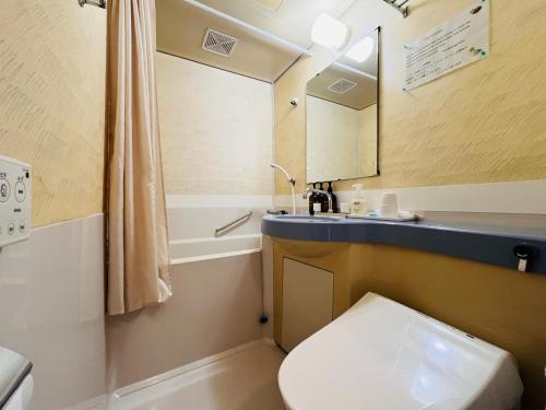 a bathroom with a toilet and a sink and a mirror at Beachside Pension Mibal in Nanjo