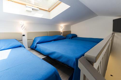 two beds in a room with blue sheets at Marechiaro Aparthotel in Marina di Camerota