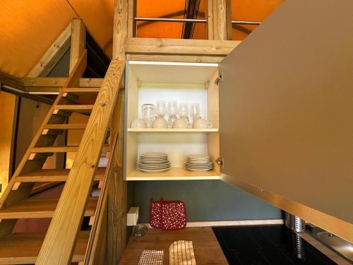 a room with stairs leading up to a loft with dishes at Glamping Camping Rivabella in Lecco