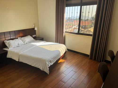 a bedroom with a bed and a large window at Kibuli beijing hotel in Kampala