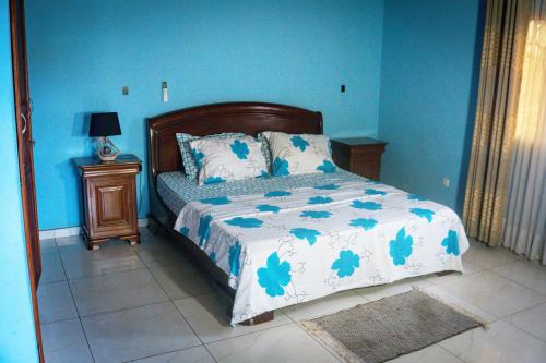 a bedroom with a bed with blue walls at Résidence Jeanne à Yaoundé Odza Messamengo in Yaoundé