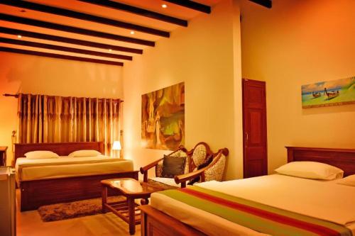 a bedroom with two beds and a desk and a chair at Lucas Hotel in Kosgoda