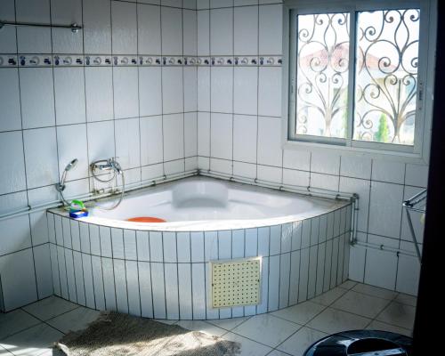 a bath tub in a bathroom with a window at Résidence Jeanne à Yaoundé Odza Messamengo in Yaoundé