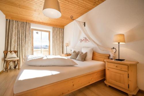 a bedroom with a large white bed with a window at Das Krumerhaus in Aschau