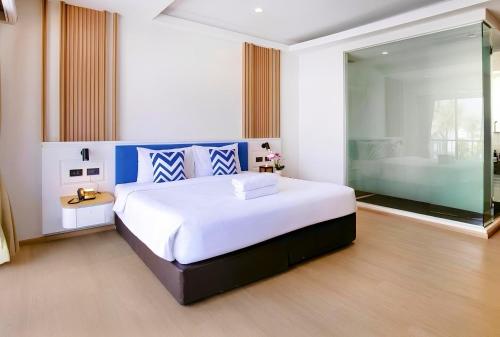 a bedroom with a large white bed and a bathroom at Citin Armoni Patong Hotel by Compass Hospitality - Newly Renovated in Patong Beach