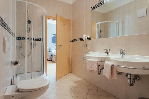 a bathroom with two sinks and a shower and a toilet at Lodenwirt Residence in Vandoies