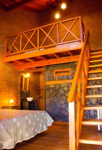 a loft bed in a room with a stone wall at Lauquen Pilmaiquen y spa in Merlo