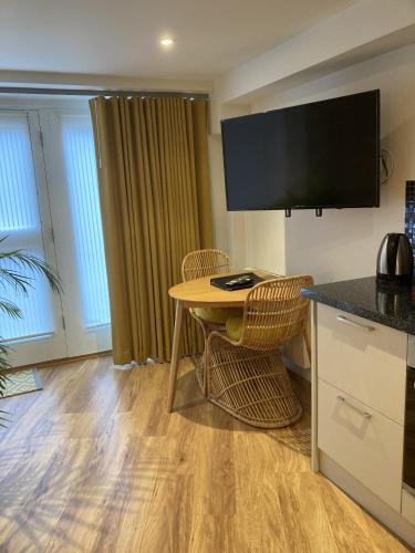 a kitchen with a table and chairs and a television at Streamside Apartments in Yeovil