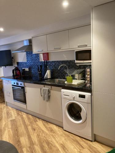 a kitchen with a washing machine and a microwave at Streamside Apartments in Yeovil