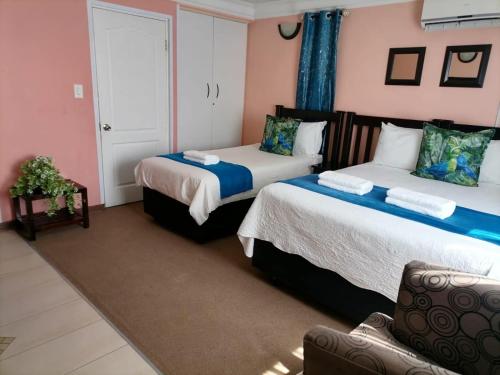two beds in a room with pink walls at Phomolo Guest House in Maseru
