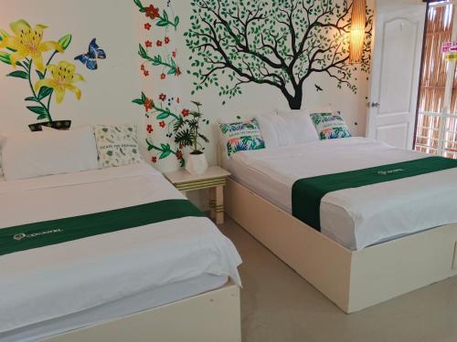two beds in a room with flowers on the wall at The Cronin Residence in Oslob