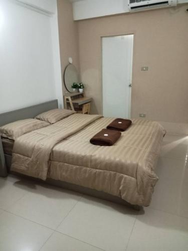 a bedroom with a bed with two brown towels on it at The City in Ban Si Than
