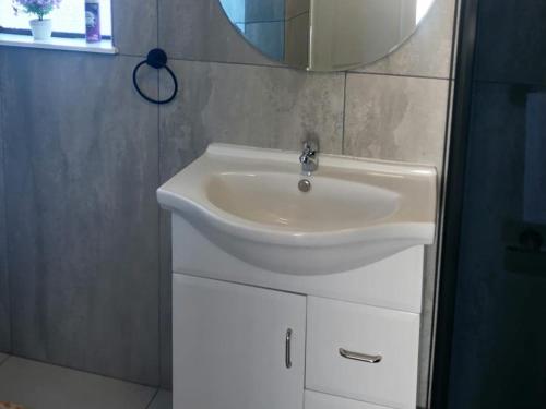 a bathroom with a white sink and a mirror at Phomolo Guest House in Maseru