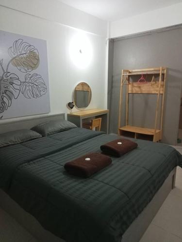 a bedroom with a green bed with two brown towels on it at The City in Ban Si Than