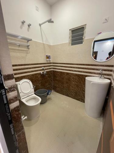 a bathroom with a toilet and a sink and a mirror at Jonaki Shantiniketan in Shānti Niketan