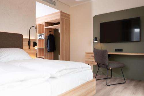 a bedroom with a bed and a desk and a television at Hotel Neue Mitte in Schlüchtern