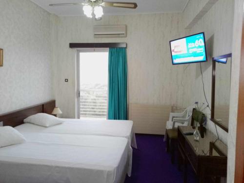 a hotel room with two beds and a flat screen tv at HOTEL ALEXANDROS in Loutraki
