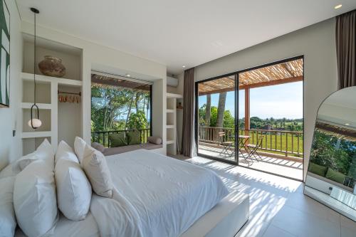 a bedroom with a large bed and a balcony at Sealuna Villas in Tanah Lot