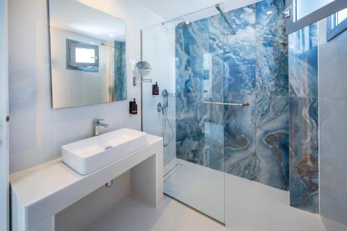 a white bathroom with a sink and a shower at Zorbas Beach Hotel in Tigaki