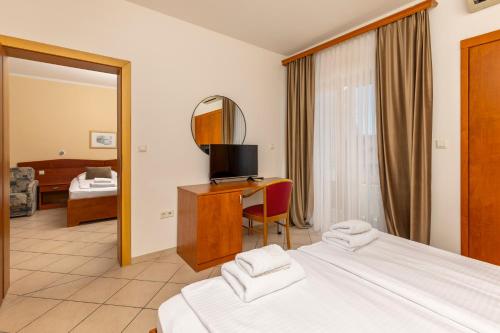 a bedroom with two beds and a desk with a mirror at Guesthouse Villa Adria in Malinska