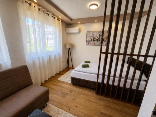 a bedroom with a bed and a couch and a window at SkyLux Premium Zenica in Zenica